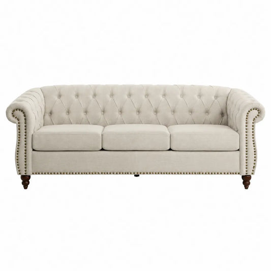 Sofá de tres plazas de tela beige con capitoné